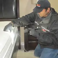 Bed bug inspection technician checking a mattress and bed frame for signs of infestation in Hollywood, FL
