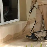 General pest control technician spraying exterior perimeter around a home in Hollywood, FL