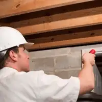 Termite inspection technician checking a basement wall and framing for termite activity in Hollywood, FL